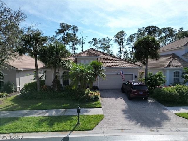 16144 Parque Ln, Naples, FL 34110 - mediterranean / spanish-style house featuring a garage, a tile roof, decorative driveway, a front yard, and stucco siding