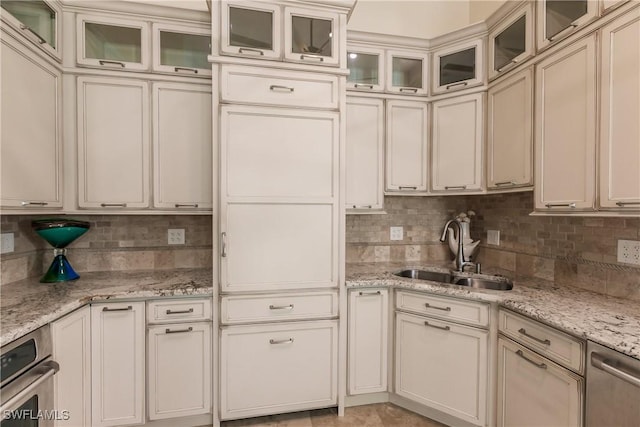 kitchen featuring sink, cream cabinets, light stone countertops, and appliances with stainless steel finishes