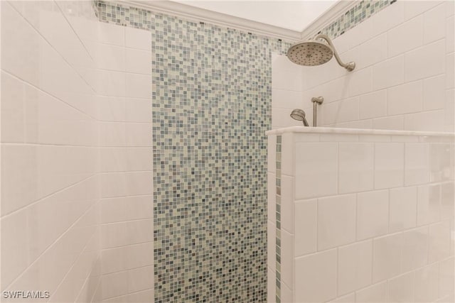 bathroom with ornamental molding and tiled shower