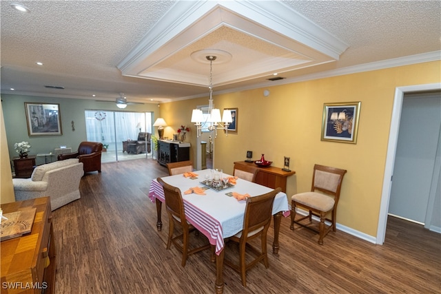 dining area featuring dark hardwood / wood-style flooring, ceiling fan with notable chandelier, a textured ceiling, a tray ceiling, and crown molding