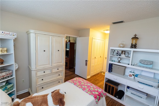 bedroom with a textured ceiling, hardwood / wood-style flooring, and a closet