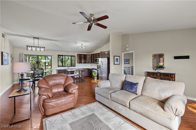 living room featuring hardwood / wood-style floors, ceiling fan with notable chandelier, and vaulted ceiling