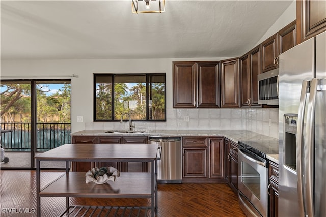 kitchen with plenty of natural light, sink, light stone countertops, and stainless steel appliances