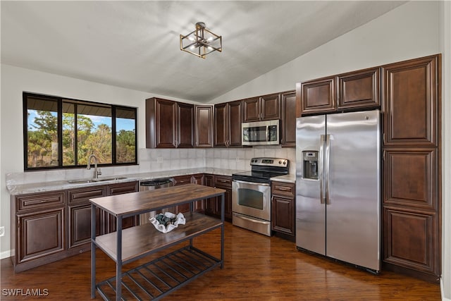 kitchen featuring sink, vaulted ceiling, dark hardwood / wood-style floors, light stone countertops, and stainless steel appliances