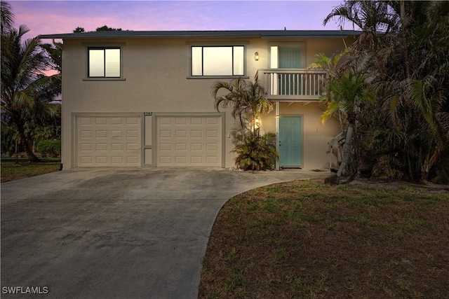 view of front of house featuring a garage, a balcony, and a yard