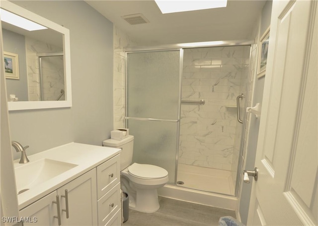 bathroom featuring toilet, vanity, a shower with shower door, and hardwood / wood-style flooring