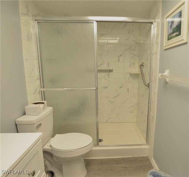 bathroom featuring walk in shower, vanity, wood-type flooring, and toilet