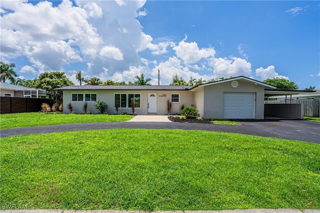 single story home with a garage, aphalt driveway, fence, a front lawn, and stucco siding