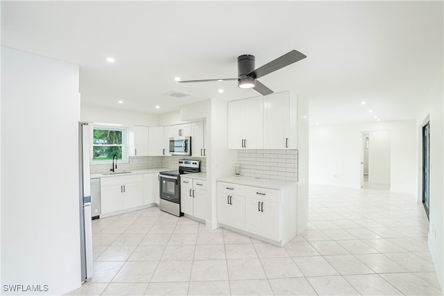 kitchen featuring ceiling fan, tasteful backsplash, light tile patterned flooring, white cabinets, and appliances with stainless steel finishes