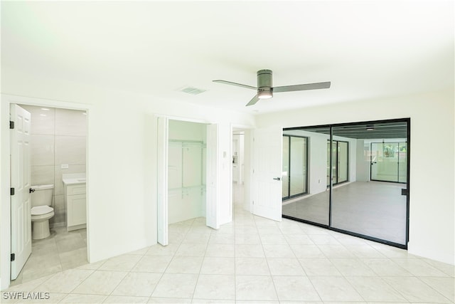 unfurnished bedroom with ensuite bathroom, ceiling fan, and light tile patterned floors