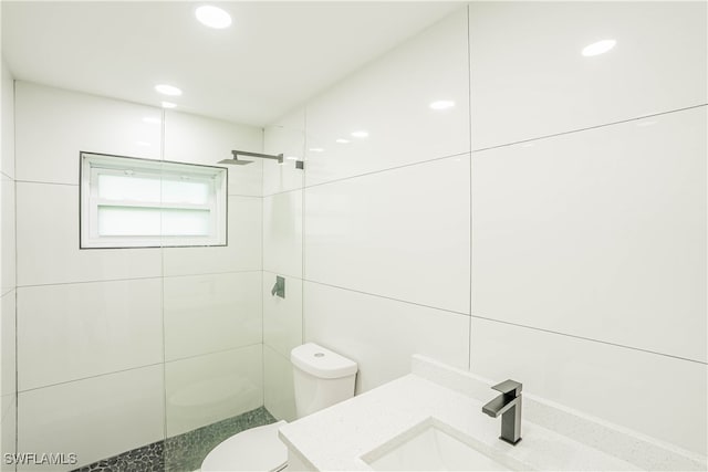 bathroom with vanity, toilet, and a tile shower