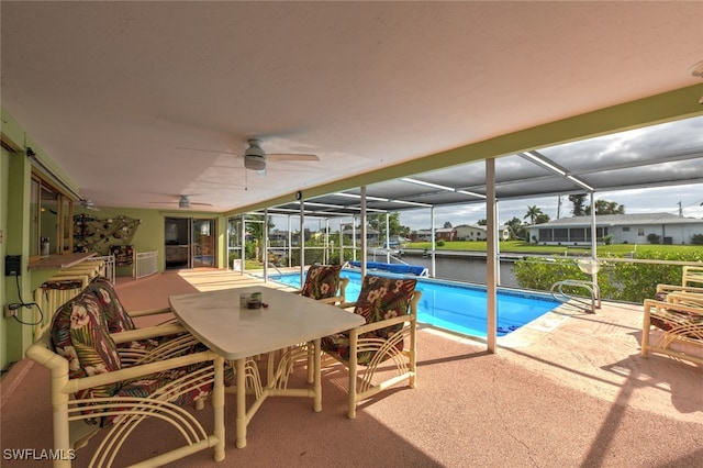 view of swimming pool featuring a water view, a patio area, ceiling fan, and a lanai