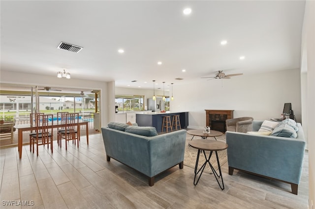 living room with ceiling fan, light hardwood / wood-style floors, and a fireplace