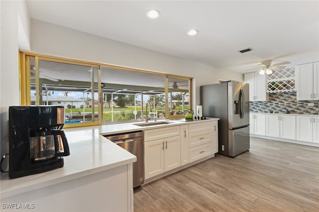 kitchen with white cabinetry, sink, stainless steel appliances, tasteful backsplash, and light hardwood / wood-style flooring