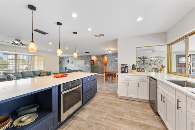 kitchen with sink, hanging light fixtures, stainless steel appliances, light hardwood / wood-style floors, and white cabinets