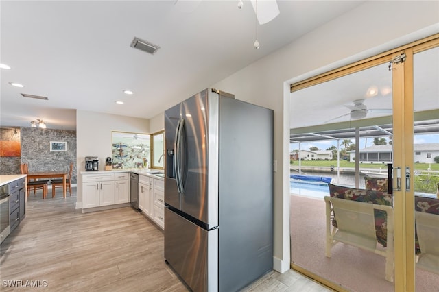 kitchen featuring stainless steel appliances, ceiling fan, sink, light hardwood / wood-style flooring, and white cabinets