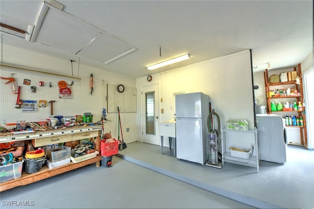 garage with a workshop area, white fridge, and washer / dryer