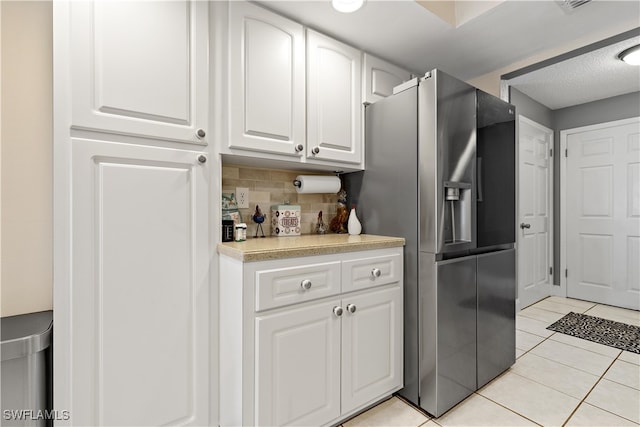 kitchen featuring backsplash, stainless steel fridge with ice dispenser, white cabinets, and light tile patterned flooring