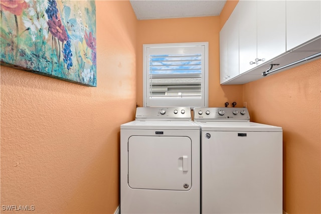 laundry area featuring washer and clothes dryer, cabinets, and a textured ceiling