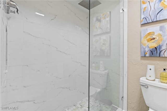 bathroom with a tile shower and toilet