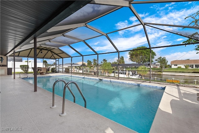 view of pool featuring glass enclosure, a water view, and a patio