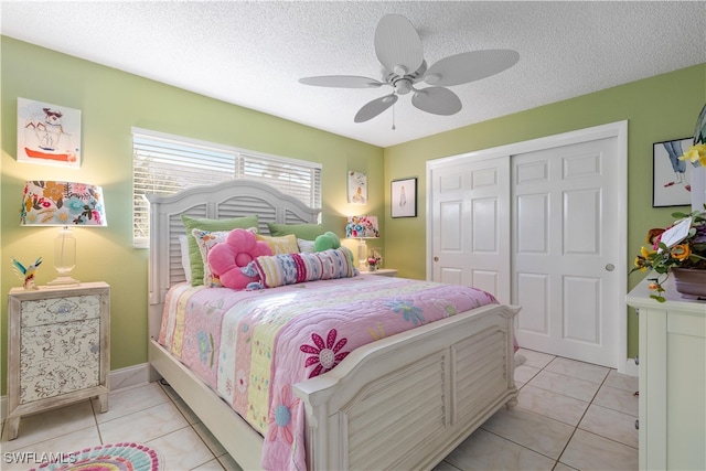 tiled bedroom with ceiling fan, a closet, and a textured ceiling