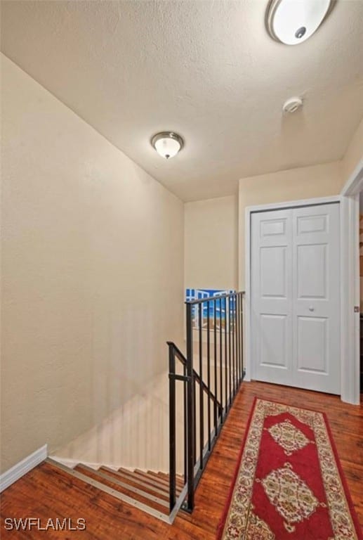 hallway featuring wood-type flooring and a textured ceiling