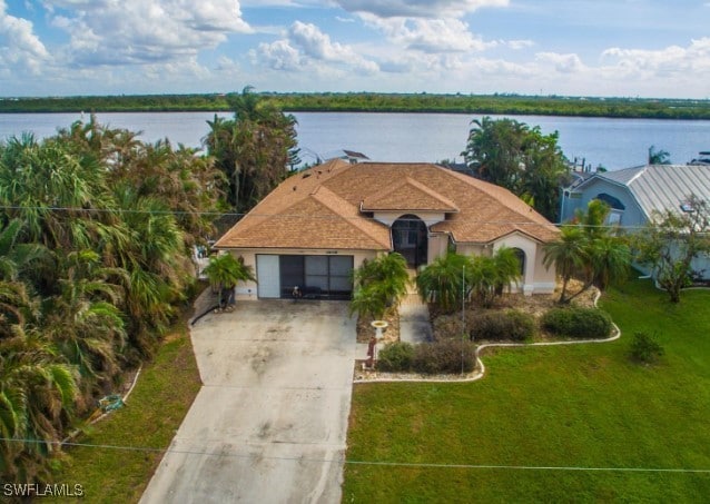 view of front of house with a garage, a water view, and a front lawn