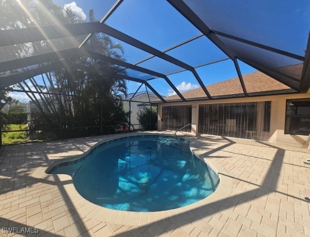 view of pool featuring glass enclosure and a patio area