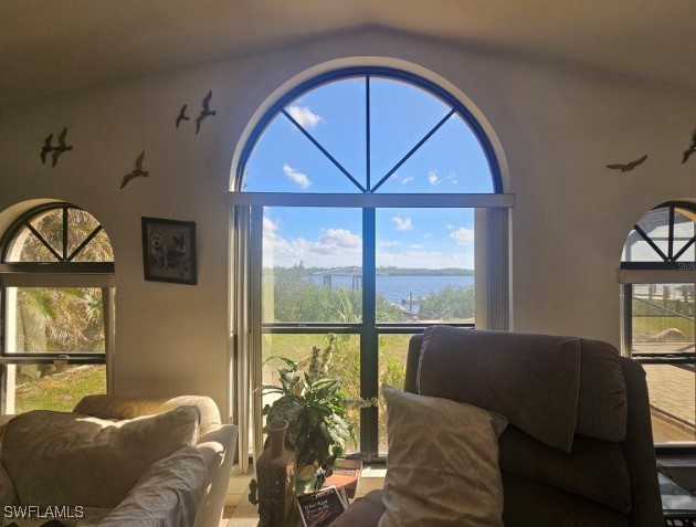 living room with plenty of natural light, a water view, and vaulted ceiling