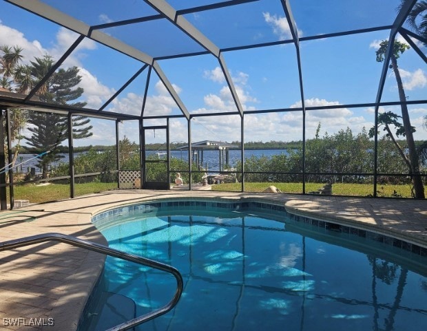 view of pool with a water view, glass enclosure, and a patio area