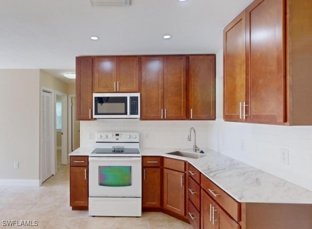 kitchen with white appliances, sink, decorative backsplash, light stone countertops, and light tile patterned floors