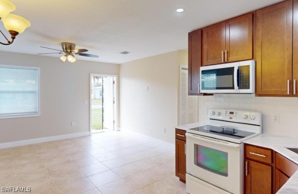 kitchen with light tile patterned floors, white appliances, ceiling fan, and backsplash