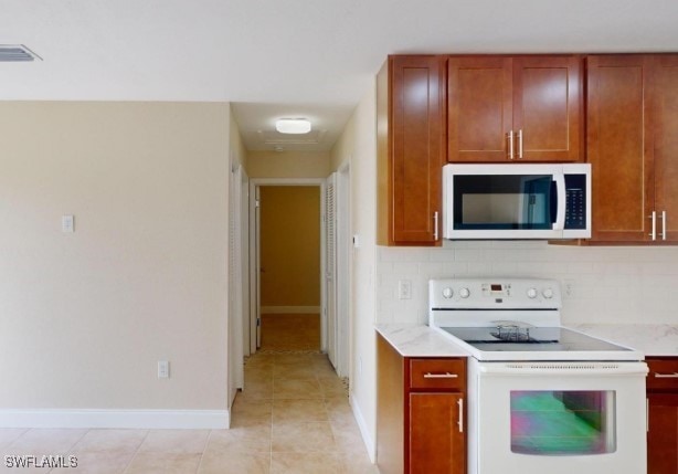 kitchen featuring light tile patterned floors, white appliances, and backsplash