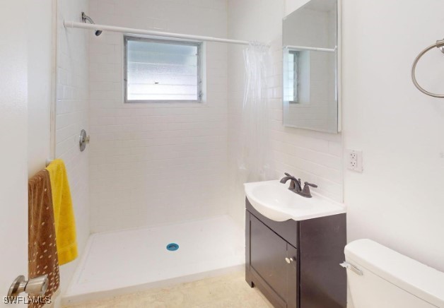 bathroom with backsplash, toilet, vanity, and walk in shower