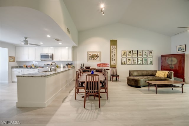 dining area featuring high vaulted ceiling, light hardwood / wood-style flooring, and ceiling fan