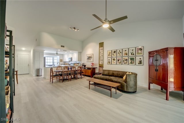 living room with ceiling fan, light wood-type flooring, and high vaulted ceiling