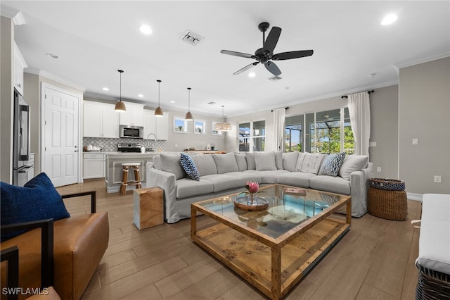 living room with ceiling fan, light hardwood / wood-style floors, and ornamental molding