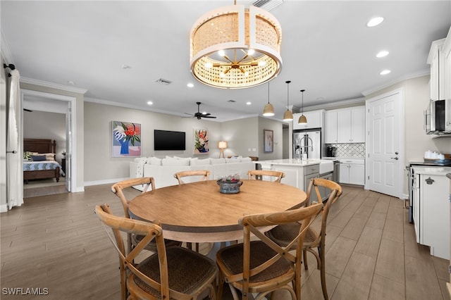 dining area featuring ceiling fan, sink, dark hardwood / wood-style flooring, and crown molding