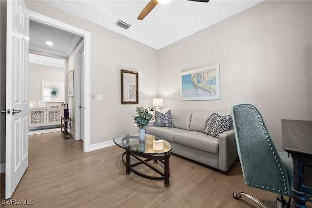 living room with light wood-type flooring, ceiling fan, and crown molding