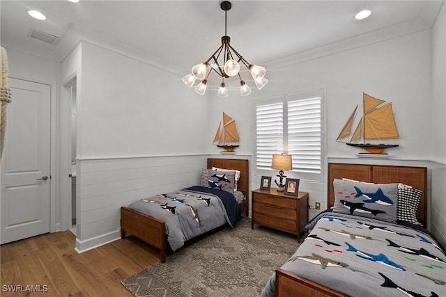 bedroom with a chandelier, ornamental molding, wood finished floors, and visible vents