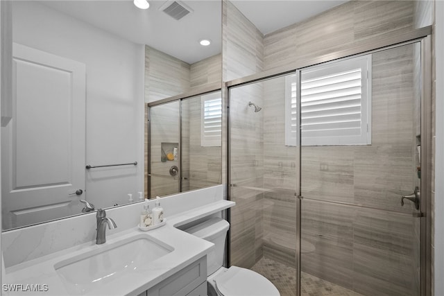 bathroom with vanity, toilet, and a shower with shower door