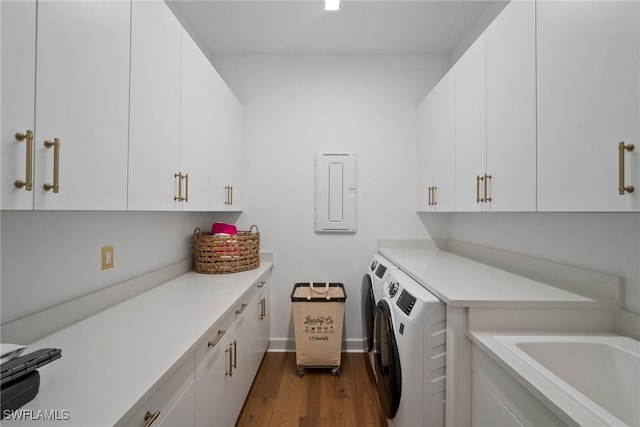 laundry room featuring washing machine and clothes dryer, electric panel, cabinets, and wood-type flooring