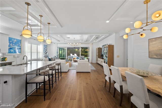 dining area with sink, an inviting chandelier, and hardwood / wood-style flooring