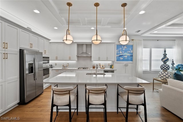 kitchen featuring pendant lighting, a kitchen breakfast bar, stainless steel refrigerator with ice dispenser, light hardwood / wood-style flooring, and wall chimney exhaust hood