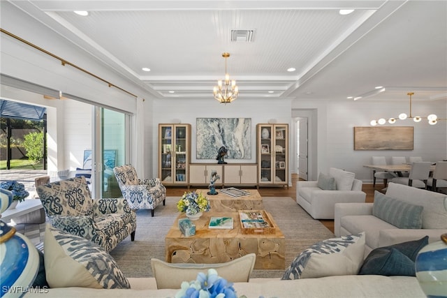 living room with hardwood / wood-style floors, a tray ceiling, and a notable chandelier