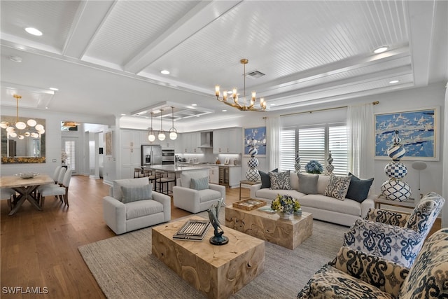 living room with sink, a raised ceiling, a notable chandelier, crown molding, and light wood-type flooring