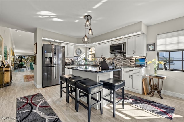 kitchen with backsplash, light hardwood / wood-style floors, stainless steel appliances, and a wealth of natural light