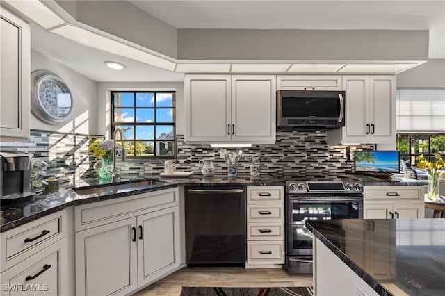 kitchen with tasteful backsplash, dark stone countertops, white cabinetry, and appliances with stainless steel finishes