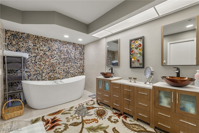 bathroom with a bathing tub, tile patterned flooring, vanity, and tile walls